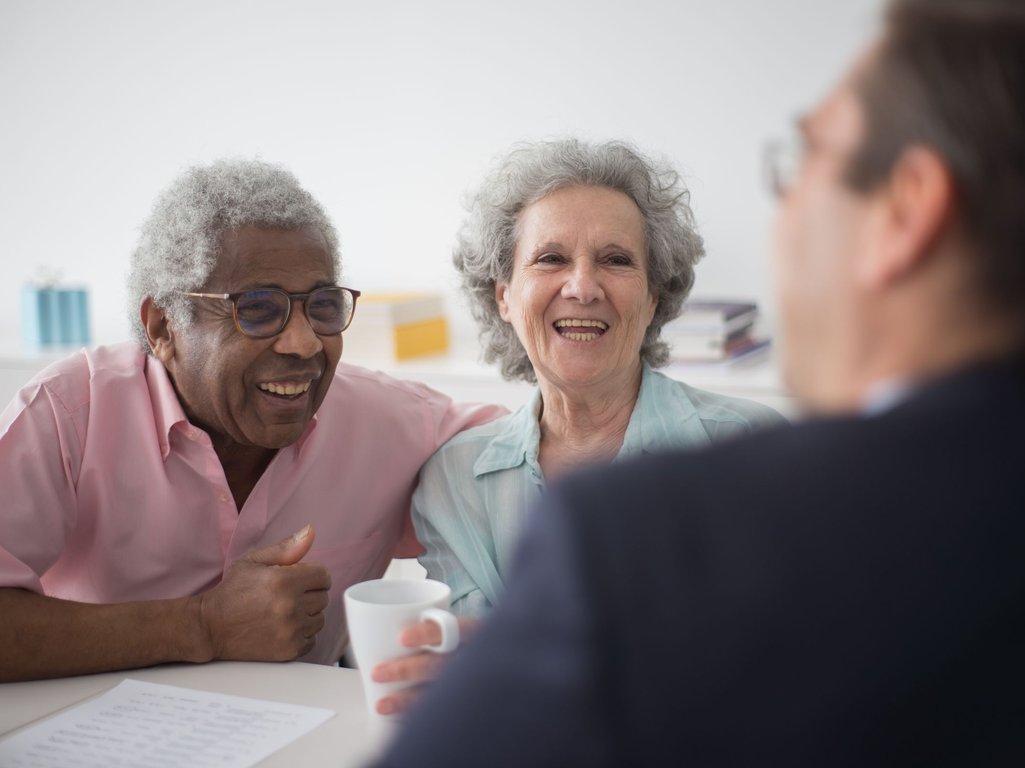 Older couple laughing while talking with an advisor